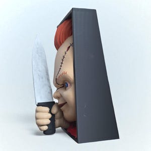 Puede incluir: Una cabeza de mu&ntilde;eco Chucky impresa en 3D con cabello rojo y detalles faciales cosidos, sosteniendo un cuchillo plateado. La mu&ntilde;eca est&aacute; parcialmente enmarcada por una estructura rectangular negra.