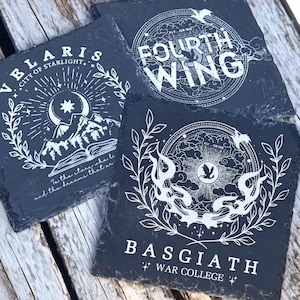 Peut inclure: Trois sous-verres en ardoise noire avec des motifs blancs. Le premier sous-verre repr&eacute;sente un croissant de lune, des &eacute;toiles et une cha&icirc;ne de montagnes avec le texte "VELARIS CITY OF STARLIGHT". Le deuxi&egrave;me sous-verre repr&eacute;sente un cercle avec le texte "FOURTH WING" &agrave; l'int&eacute;rieur. Le troisi&egrave;me sous-verre repr&eacute;sente un cercle avec le texte "BASGIATH WAR COLLEGE" &agrave; l'int&eacute;rieur.