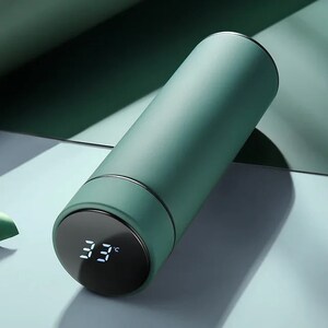A green cylindrical thermos with a digital temperature display showing 33°C on its lid, placed on a white surface.