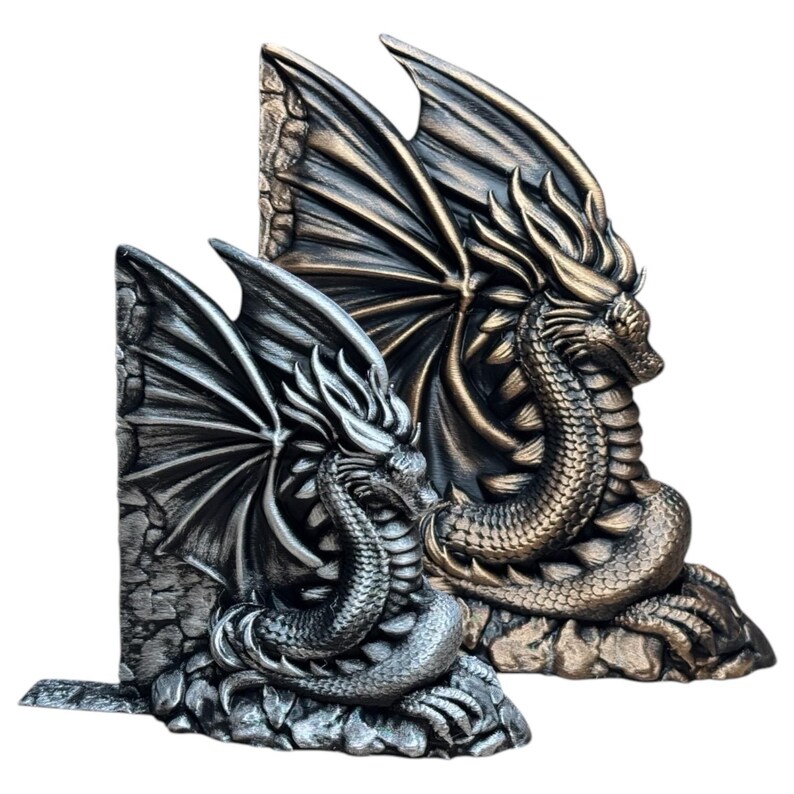 May include: Two dragon bookends, one silver and one gold, with wings outstretched and curled tails. They are both sitting on a rocky base.
