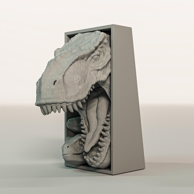 K&ouml;nnte beinhalten: Eine graue, dreidimensionale Skulptur eines Tyrannosaurus Rex-Kopfes, der aus einem rechteckigen Rahmen herausragt. Das Maul des Dinosauriers ist ge&ouml;ffnet und zeigt scharfe Z&auml;hne und ein detailliertes Inneres. Die Skulptur ist in einem neutralen Grauton gehalten.
