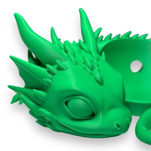 Pode incluir: Um vaso de drag&atilde;o impresso em 3D de cor verde brilhante com um pequeno furo no topo para drenagem. O drag&atilde;o est&aacute; enrolado com a cabe&ccedil;a apoiada na cauda.