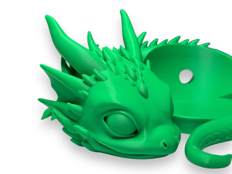 Pode incluir: Um vaso de drag&atilde;o impresso em 3D de cor verde brilhante com um pequeno furo no topo para drenagem. O drag&atilde;o est&aacute; enrolado com a cabe&ccedil;a apoiada na cauda.