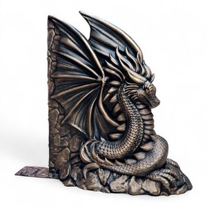 May include: A bronze dragon bookend with wings spread wide, perched on a rocky base. The dragon's head is turned to the side, and its scales are detailed.