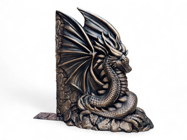 May include: A bronze dragon bookend with wings spread wide, perched on a rocky base. The dragon's head is turned to the side, and its scales are detailed.