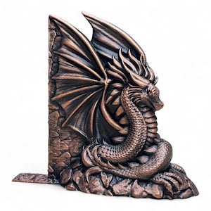 May include: A bronze dragon bookend with wings outstretched, perched on a rocky base. The dragon's head is turned to the side, and its scales are detailed.