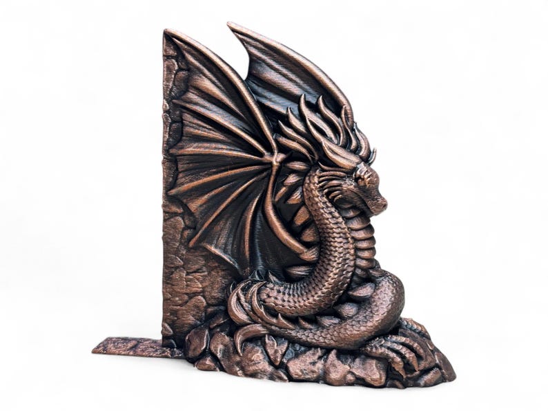 May include: A bronze dragon bookend with wings outstretched, perched on a rocky base. The dragon's head is turned to the side, and its scales are detailed.