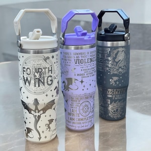 May include: Three stainless steel travel mugs with different designs. The first mug is white with a silver dragon and the text "Fourth Wing". The second mug is lavender with a silver dragon and text about dragons and riders. The third mug is gray with a silver dragon and the text "Only if you are fascinated by the power of this dragon will it without you".