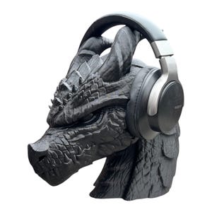 K&ouml;nnte beinhalten: Eine schwarze Drachen-Skulptur mit einem schwarzen und silbernen Kopfh&ouml;rer auf dem Kopf.