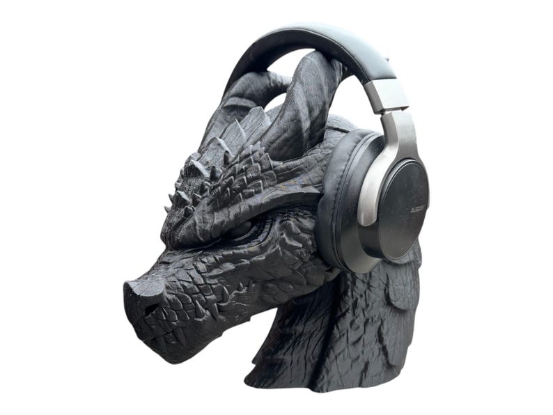 K&ouml;nnte beinhalten: Eine schwarze Drachen-Skulptur mit einem schwarzen und silbernen Kopfh&ouml;rer auf dem Kopf.