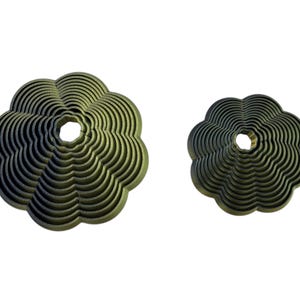 May include: Two olive-green, flower-shaped decorative objects. The larger one has a diameter of approximately 15 cm, while the smaller one is about 10 cm across. Both have a central hole and a layered, wavy design.