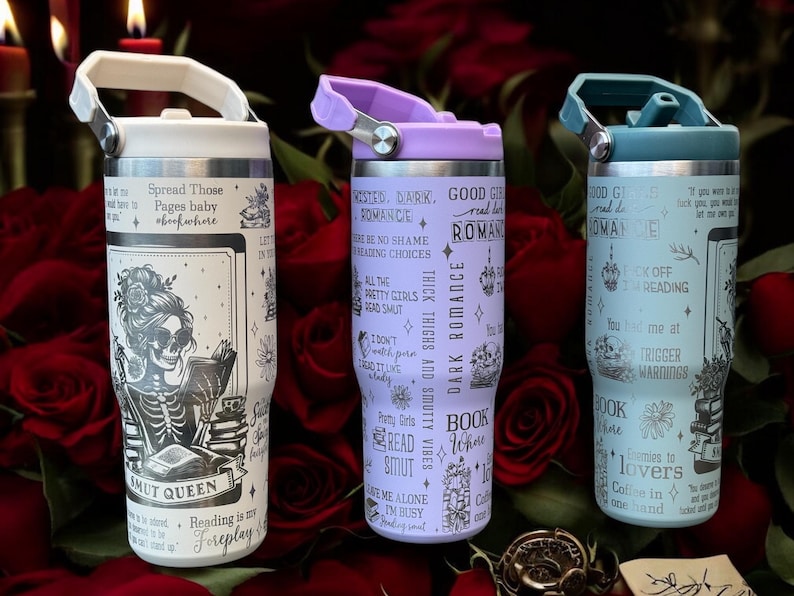 May include: Three stainless steel tumblers with different designs. The white tumbler features a skeleton reading a book with the text "Spread Those Pages Baby" and "Smut Queen". The purple tumbler features a dark romance theme with the text "Dark Romance" and "Book Lovers". The blue tumbler features a dark romance theme with the text "Good Girls Read Bad Romance" and "Trigger Warnings".