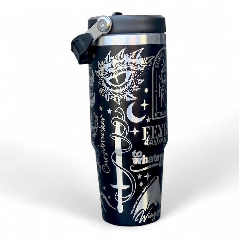 May include: Black insulated travel mug with a black lid and handle. The mug has silver etched designs including a sword, crescent moons, stars, and text that reads "Feyre darling to whatever".