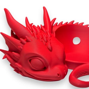 Pode incluir: Uma figura de drag&atilde;o vermelha brilhante, impressa em 3D, com cauda enrolada e olhos fechados. O drag&atilde;o tem uma superf&iacute;cie detalhada e texturizada e &eacute; projetado para ser um objeto decorativo.