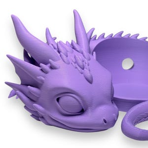 Pode incluir: Um vaso de drag&atilde;o impresso em 3D roxo com um design de drag&atilde;o dormindo. O vaso tem um pequeno furo na parte de tr&aacute;s para pendurar.
