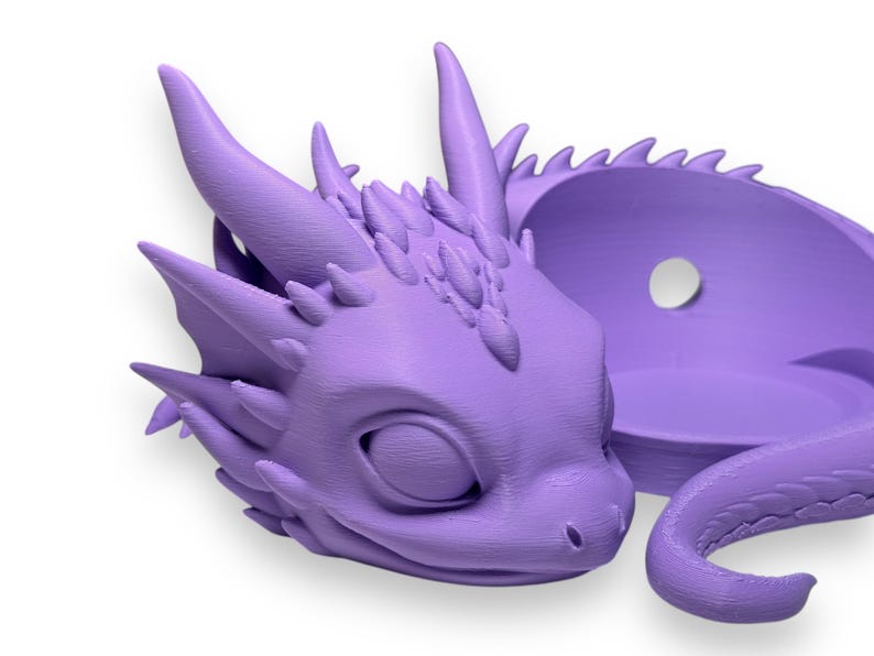 Pode incluir: Um vaso de drag&atilde;o impresso em 3D roxo com um design de drag&atilde;o dormindo. O vaso tem um pequeno furo na parte de tr&aacute;s para pendurar.