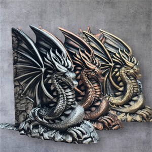 May include: Three dragon bookends in different metallic finishes: silver, copper, and gold. Each dragon is sculpted with intricate details, including wings, scales, and claws. The bookends are a decorative and functional addition to any bookshelf.