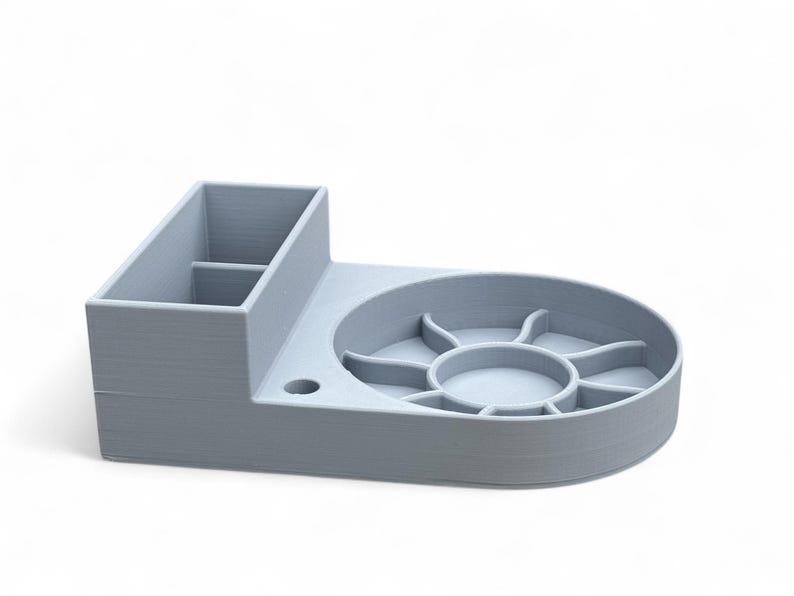 May include: A light gray desktop organizer with a compartment for pens and pencils, a circular tray with multiple compartments, and a small hole for a cable.