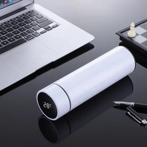 A white cylindrical thermos with a digital temperature display showing 33°C on its lid, placed on a white surface.