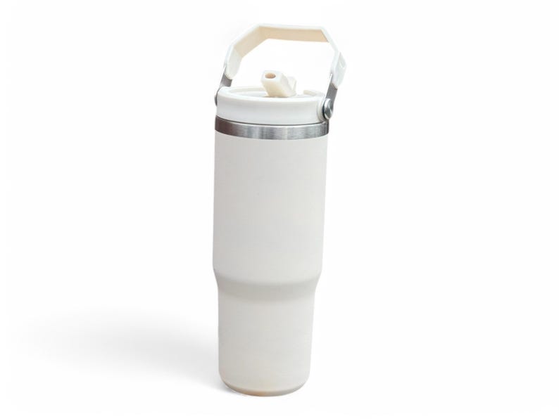 May include: A white insulated travel mug with a handle and a straw lid. The mug has a stainless steel band around the middle.