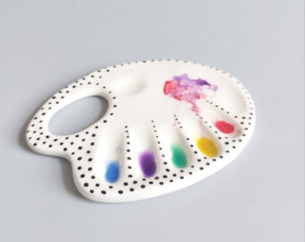 May include: White ceramic paint palette with black polka dots and six paint wells. The wells are filled with blue, purple, green, yellow, red, and pink paint.