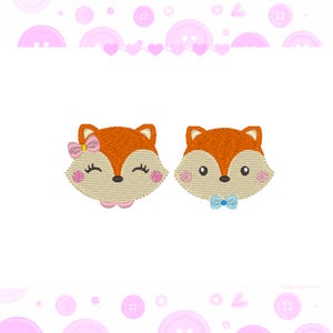 May include: Two embroidered fox faces, one with a pink bow and the other with a blue bow. The foxes have orange fur, brown noses, and black eyes.
