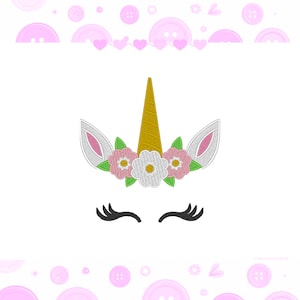 Pode incluir: Um design de unicórnio caprichoso com um chifre dourado, orelhas brancas e rosa e uma coroa floral com flores rosa e brancas. Cílios pretos completam o design. A imagem está em um fundo branco.