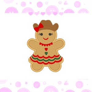 May include: Embroidered gingerbread cookie in the shape of a person, wearing a brown cowboy hat with a red bow, a red heart necklace, and a green and red dress. The cookie has a smiling face and is on a white background.