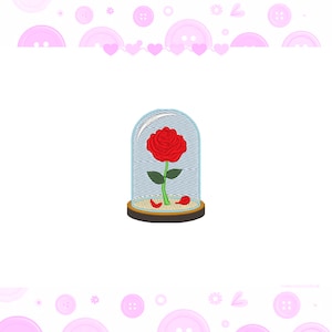 Può includere: Una rosa rossa con foglie e stelo verdi, racchiusa in una cupola di vetro con base in legno. Petali caduti intorno alla base. Sfondo bianco con bottoni e cuori rosa.