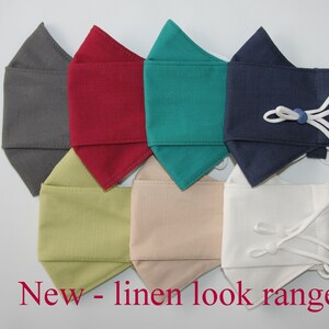 May include: Seven face masks in different colors, including gray, red, teal, navy, light green, beige, and white. The masks are made of a linen-like fabric and have adjustable ear loops. "New - linen look range" is written in red text at the bottom of the image.