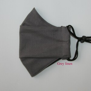 May include: A gray linen face mask with black adjustable straps. The mask has a simple design and is made of a soft, breathable fabric.  Grey linen.