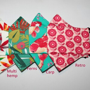 Puede incluir: Cuatro mascarillas de tela diferentes con varios patrones. Las mascarillas est&aacute;n dobladas y dispuestas en fila. Los patrones son: multi c&aacute;&ntilde;amo, helechos, carpa y retro.