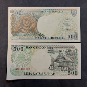 May include: Indonesian 500 Rupiah banknote featuring an orangutan on the front and a traditional house on the back. The text "LIMA RATUS RUPIAH" is printed on both sides.