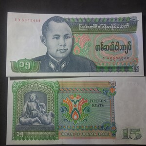 May include: Two Burmese banknotes. The top note displays a portrait and Burmese script, with the number 15 in the corners. The bottom note features a seated figure, floral designs, and the text "FIFTEEN KYATS".