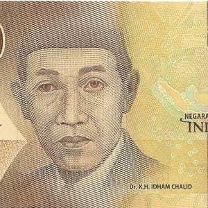 Könnte beinhalten: Ein gelber indonesischer 5.000 Rupiah-Geldschein. Der Schein zeigt ein Porträt von Dr. K.H. Idham Chalid, den Text "5000 LIMA RIBU RUPIAH" und das indonesische Wappen. Der Schein ist von 2016.