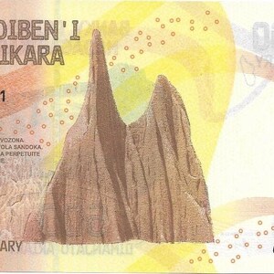 May include: A 500 Ariary Malagasy banknote featuring a brown and yellow design with a mountain range in the centre. The text "BANKY FOIBEN'I MADAGASIKARA" is printed at the top of the note. The serial number "C00160991" is printed in the top left and bottom right corners.