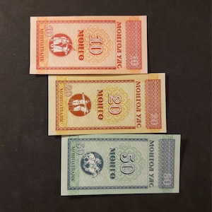 May include: Three Mongolian banknotes, one each for 10, 20, and 50 Mongolian tugrik. The banknotes are in red, yellow, and green, respectively. Each banknote features a different image of Mongolian people and horses.
