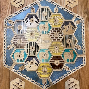 May include: Wooden board game with a hexagonal design. The game board features various terrain tiles, including forests, mountains, and fields, with numbers and resource symbols. The game includes wooden hexagonal pieces and smaller wooden tokens. The text "MACKENZIE" is visible.