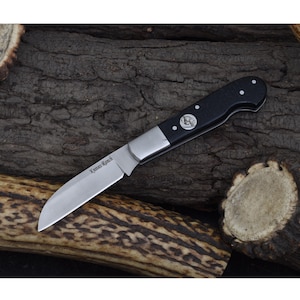May include: A black handled folding knife with a stainless steel blade. The blade is engraved with "Knives Ranch".