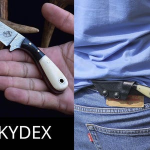 May include: A small knife with a Damascus steel blade and a black and cream handle. The knife is shown in a hand and in a black sheath attached to a pair of blue jeans. The word "KYDEX" is displayed in white text.