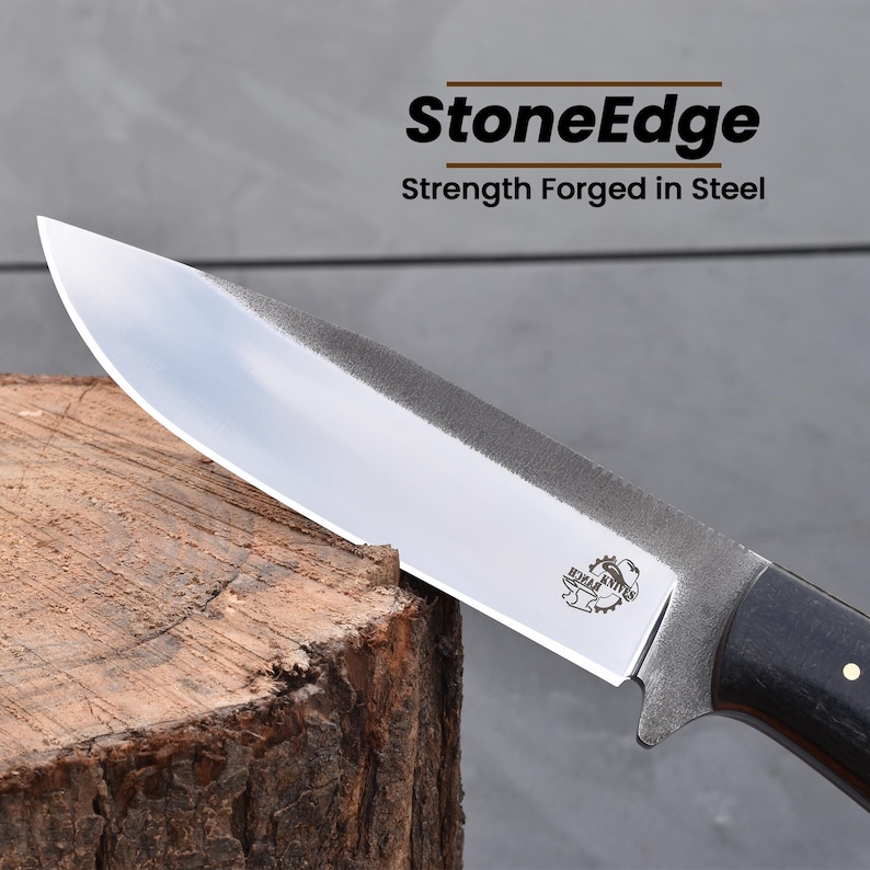 Puede incluir: Primer plano de un cuchillo plateado con mango de madera negra. El cuchillo est&aacute; apoyado en un toc&oacute;n de &aacute;rbol. La hoja tiene un logotipo de StoneEdge grabado. El texto "Strength Forged in Steel" est&aacute; impreso sobre el logotipo.