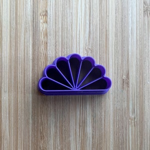 Puede incluir: Cortador de galletas de pl&aacute;stico morado en forma de abanico con siete secciones.