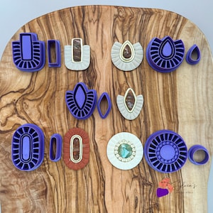 Peut inclure: Un ensemble de 11 emporte-pièces en plastique violet de différentes formes, notamment des cercles, des ovales et des fleurs. Les emporte-pièces sont disposés sur une surface en bois.