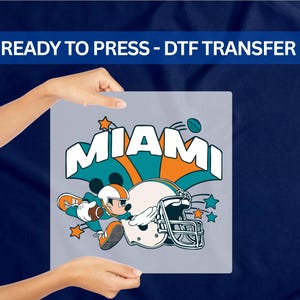 A person's hands holding a sign with the text "MIAMI" and an illustration of Mickey Mouse holding a football.