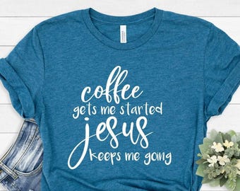 May include: A heathered teal short-sleeve t-shirt featuring white text that reads, coffee gets me started jesus keeps me going. The shirt has a crew neckline and a standard fit, with the graphic printed in a mix of script and sans-serif fonts.