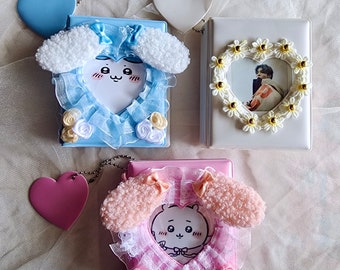 May include: Three photo albums with different designs. The first album is light blue with a white fluffy heart-shaped frame and a cartoon puppy face. The second album is white with a heart-shaped frame decorated with white flowers and a photo of a person inside. The third album is pink with a white fluffy heart-shaped frame and a cartoon puppy face.