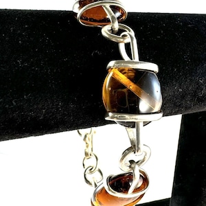 May include: A silver chain bracelet with three amber glass beads. The beads are set in silver frames.