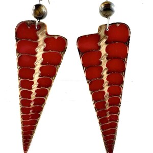 May include: A pair of red and brown geometric earrings with a textured surface. The earrings are made of metal and have a silver bead at the top.