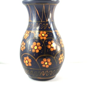 May include: A blue ceramic vase with a floral pattern. The vase has a narrow neck and a wide base. The flowers are orange and yellow.