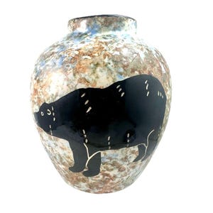Peut inclure: Un vase en céramique avec un extérieur moucheté marron, bleu et blanc. Une grande silhouette d'ours noir est peinte sur le devant, avec des accents blancs. Le vase a un corps arrondi et un col étroit, idéal pour la décoration intérieure.